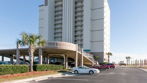 Un hotel de varios pisos con un atrio central, zona de estacionamiento y vistas a la playa.