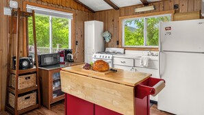 Una cocina con paredes de madera, estufa a gas, microondas, refrigerador y mostrador de madera.