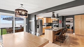 A modern kitchen with a large island, stainless steel appliances, and a view of the outdoors. - Cozy cabin with 100 ft of lake shore in the heart of the brainerd lakes area! (Brainerd)