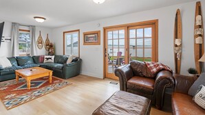 A living room with leather sofas, a wooden coffee table, and a large window with a view of the sea. - Cozy cabin with 100 ft of lake shore in the heart of the brainerd lakes area! (Brainerd)