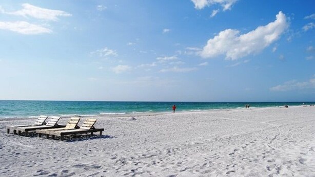A beach with white sand, a clear blue sky, and a few lounge chairs. - Wake to the Sunrise and Steps to the Sunset! Best of Both Worlds! (Indian Rocks Beach)
