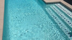Une piscine rectangulaire à l’eau d’un bleu limpide, dont les bords sont recouverts de carreaux.