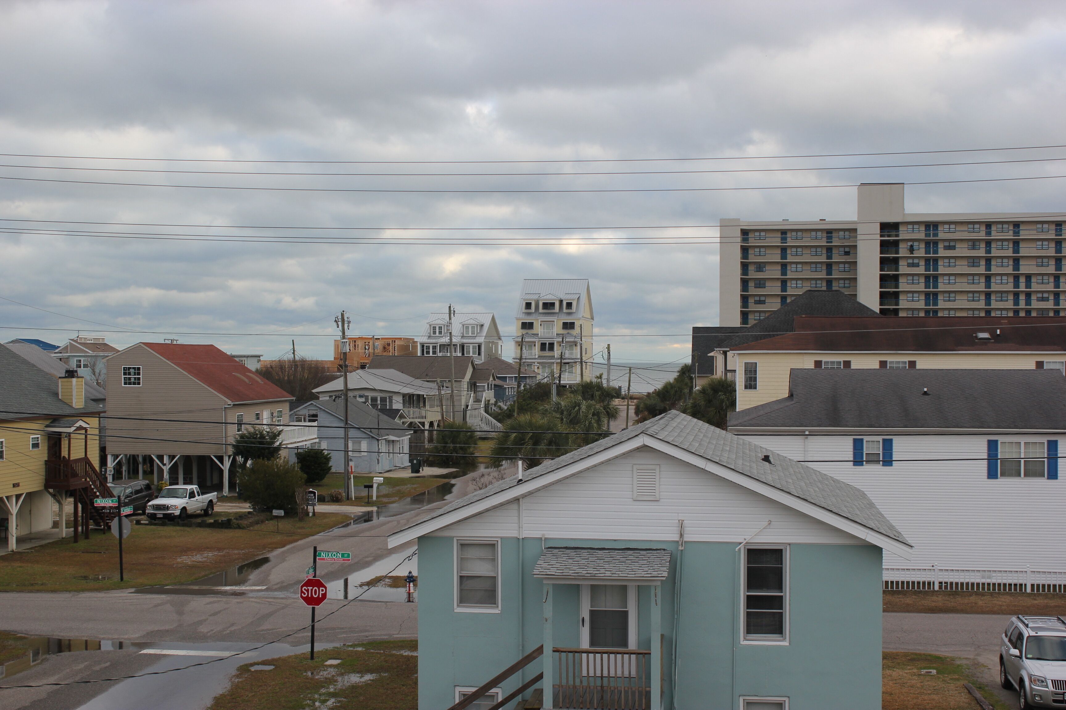 Un quartier résidentiel avec des maisons, un panneau de signalisation et une vue sur l’océan.