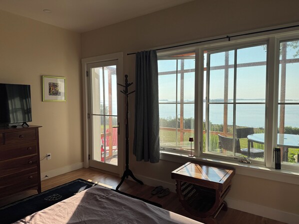 A bedroom with a large window, a bed, a dresser, and a coat rack.
