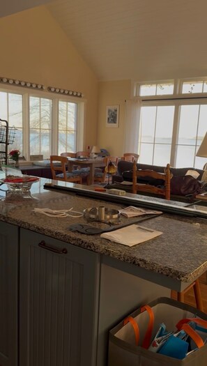 A kitchen with a granite countertop, a dining area with chairs and a table, and a large window providing natural light.