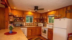 Una cocina con armarios de madera, un microondas, un refrigerador y una estufa.