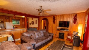 Una sala acogedora con un sofá de cuero marrón, una mesa de centro de madera y un televisor.