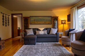 A living room with a dark sofa, a patterned rug, and a painting on the wall.