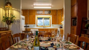 A dining area with a table set for a meal, wooden cabinets, and a window with a view.