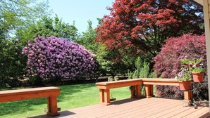 A wooden deck with benches and potted plants.