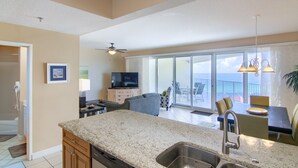 A spacious kitchen with a large island, a dining area with a table and chairs, and a balcony with a view. - 9th Floor Beach Front Condo Tides @ Topsl (Destin)