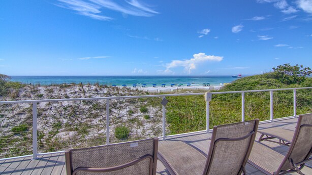 A deck with wicker chairs overlooking a beach with umbrellas and a clear blue sky. - 9th Floor Beach Front Condo Tides @ Topsl (Destin)