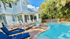 Zona de piscina con sillones reclinables y terraza.