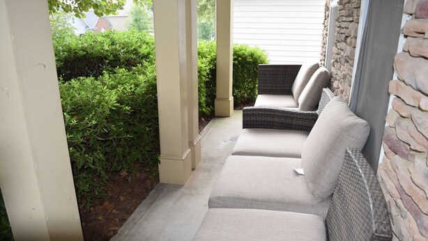 A covered outdoor seating area with wicker furniture and a stone wall. - Modern 4BR Retreat — Minutes from Mercedes-Benz Stadium - World Cup Ready (Atlanta)