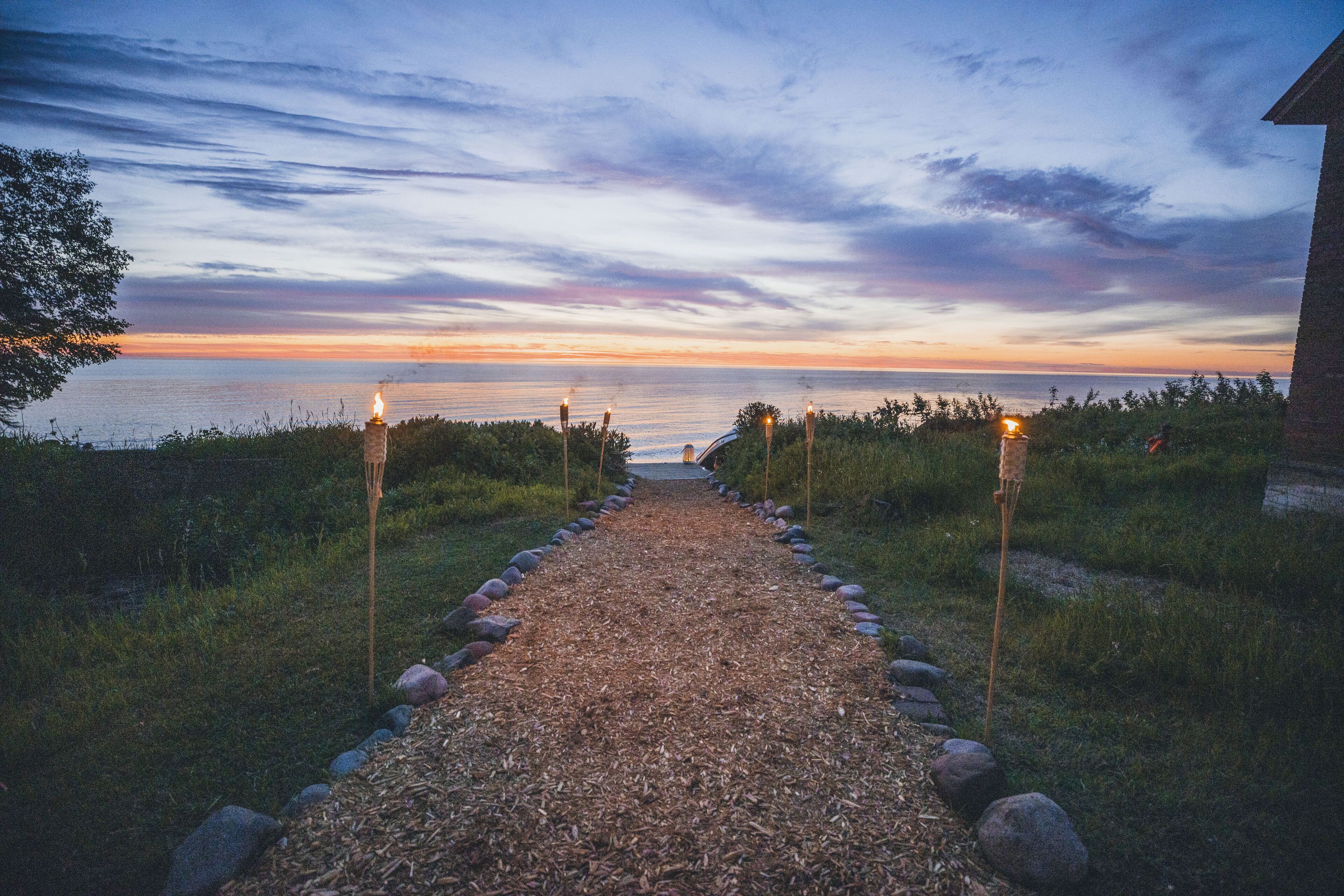 A gravel path leading to a building with a view of the ocean at sunset.