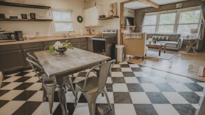 A kitchen with a checkered floor, a dining table with chairs, and a sofa in the adjacent living area.