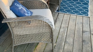 A covered outdoor seating area with wicker furniture and cushions.