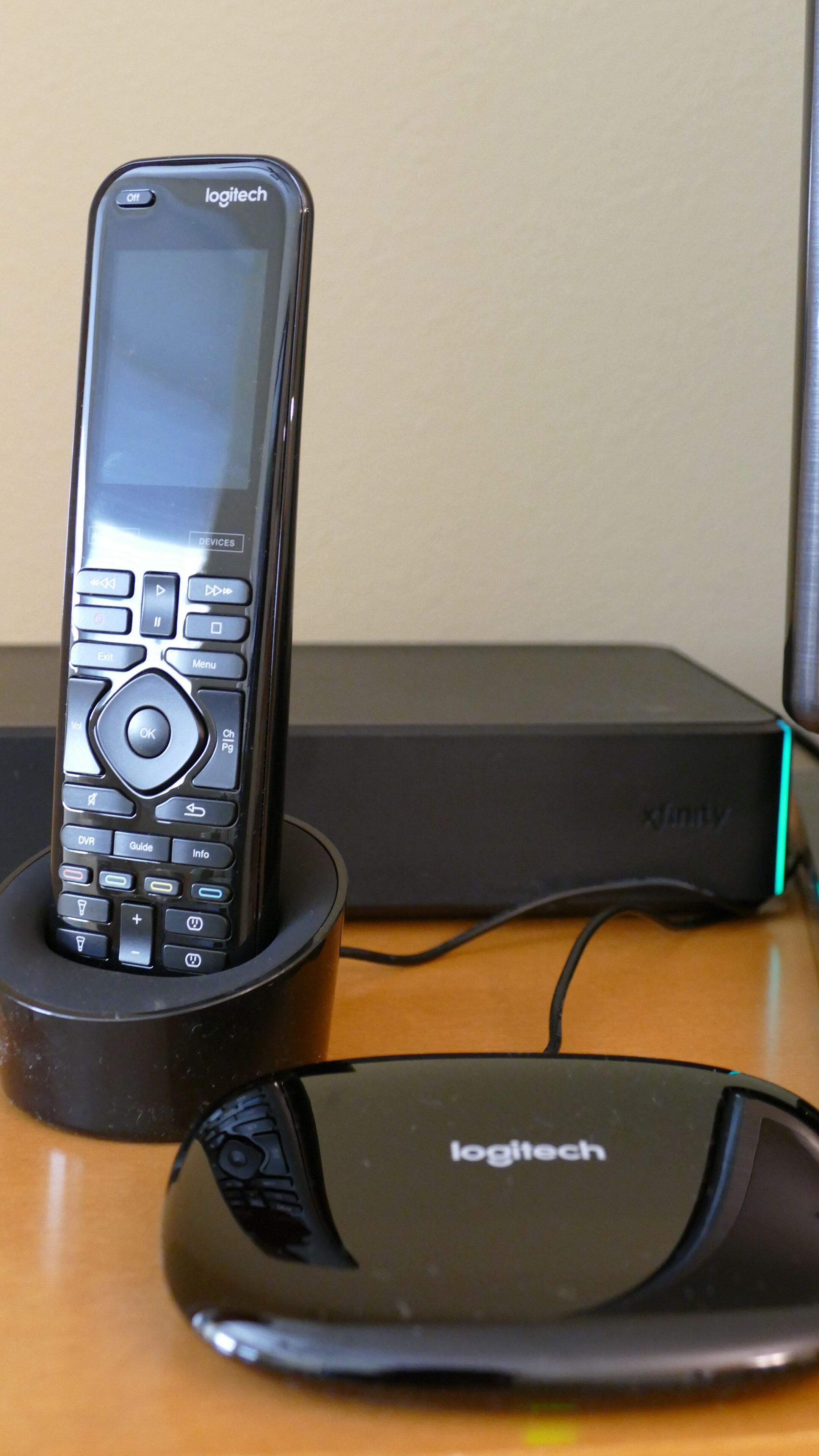 Un ratón inalámbrico Logitech y un control remoto alámbrico Logitech sobre un escritorio de madera.