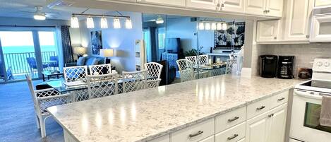 Una cocina moderna con armarios blancos, una isla grande y vistas a un balcón.
