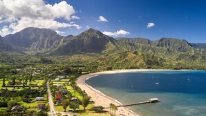 A coastal landscape with a beach, clear blue waters, and a mountainous backdrop. - Ocean view Steps to Hanalei Beach TVNC#5087 (Hanalei)