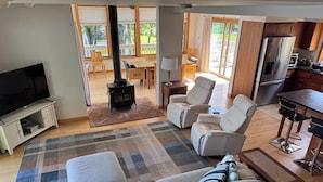 A living room with a sofa, chairs, a TV, a fireplace, and a kitchen area. - Lakefront Retreat near Saratoga Racetrack, SPAC (Malta)