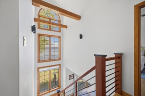 Un escalier avec des rampes en bois et de nombreuses fenêtres.