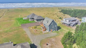 Une propriété située sur la côte, comprenant une grande maison, un garage et un bâtiment séparé doté d’une terrasse.