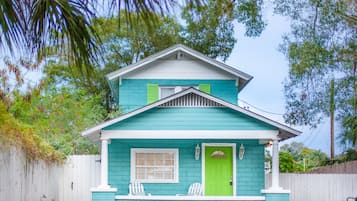 Une maison à deux étages, avec une façade de couleur turquoise et des éléments décoratifs blancs.