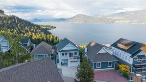 Un quartier résidentiel avec des maisons, un lac et des montagnes en arrière-plan.