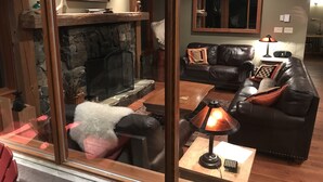 Ein gemütliches Wohnzimmer mit Kamin aus Stein, Ledersofas und einem Holztisch.