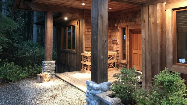 Eine Holzhütte mit überdachter Veranda, einem Schild mit der Aufschrift 'Telford View House' und einem Holzstapel davor.