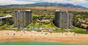 Un complexe hôtelier comprenant deux immeubles de grande hauteur, une plage et un espace piscine.