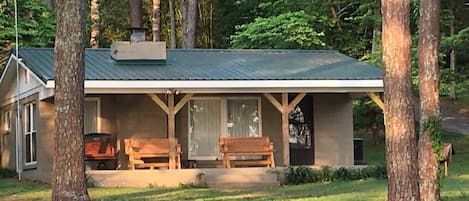 A cabin with a porch, two wooden benches, and a metal roof.
