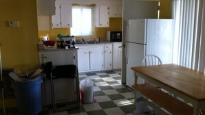Une cuisine de taille réduite avec des meubles blancs, un four à micro-ondes, un réfrigérateur et un carrelage à motifs à carreaux.