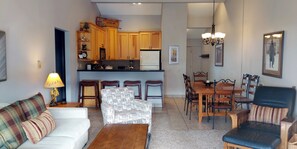 A living room with a sofa, armchair, and a dining area with a table and chairs.
