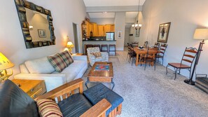 A living room with a sofa, coffee table, and a dining area with a table and chairs.