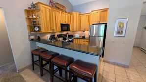 A kitchen with wooden cabinets, a stainless steel refrigerator, a microwave, a coffee maker, and a clock on the wall. - Remodeled Condo w/ FREE WiFi, Parking, Heated Pool, Hot Tubs, Skier Shuttles (Avon)
