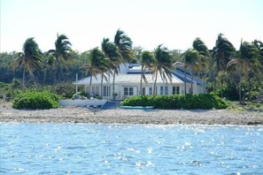 A beachfront property with a white building, palm trees, and a clear view of the ocean. - Oceanfront, Pool, Gourmet Kitchen, 2 BR, Office with Futon. (Bamboo Bay)