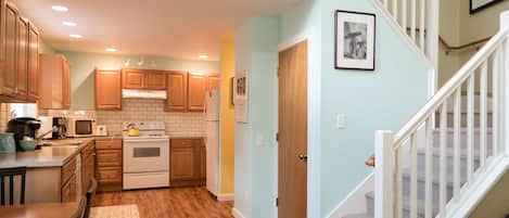 A kitchen with wooden cabinets, a microwave, stove, and a refrigerator.
