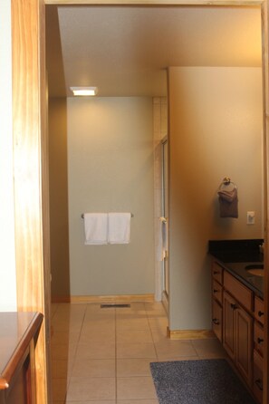 A narrow hallway with a shower, a towel rack, and wooden cabinets. - Views of Grand Lake, Shadow Mountain Lake and RMNP! (Grand Lake)