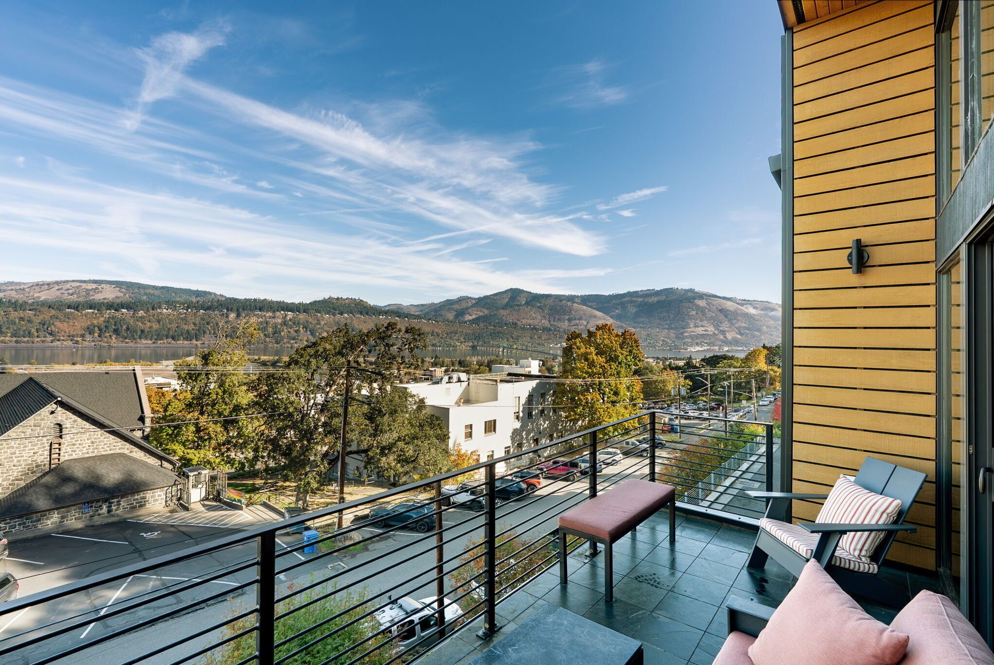 A balcony with a view of a parking lot and mountains.
