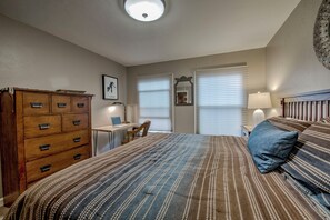 A bedroom with a bed, dresser, desk, chair, and two bedside lamps.