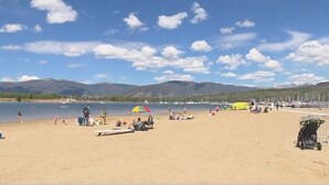 Une plage avec des gens, des bateaux et des montagnes en arrière-plan.