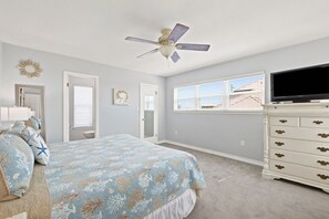 A bedroom with a bed, dresser, ceiling fan, and a window.