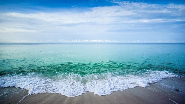 A beach with clear turquoise water and a sandy shore.