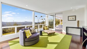 A modern living room with large windows, a curved sofa, a small table, and a view of the outdoors. - As featured on CBS's Staycation!
Luxury Retreat Overlooking Sonoma Valley (Glen Ellen)