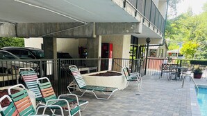 Zona junto a la piscina con sillones, una piscina pequeña y un área de estar cubierta.
