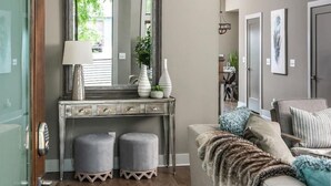 Een woonkamer met een grijze bank, een grote spiegel en een console met decoratieve objecten.