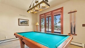 Une table de billard avec un cadre en bois, une lampe et un tableau encadré accroché au mur.