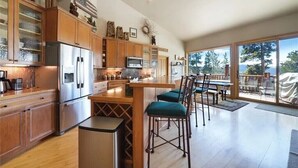 Une cuisine moderne avec des meubles en bois, des appareils en acier inoxydable et un coin bar équipé de tabourets.